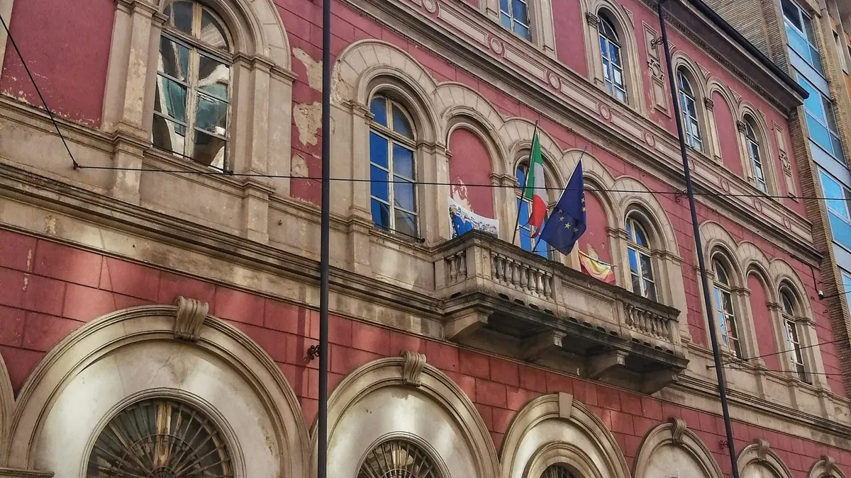 Facciata storica di un edificio scolastico con le bandiere italiana ed europea