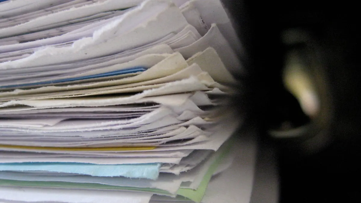 Una pila di fogli e fascicoli di carta visti di lato