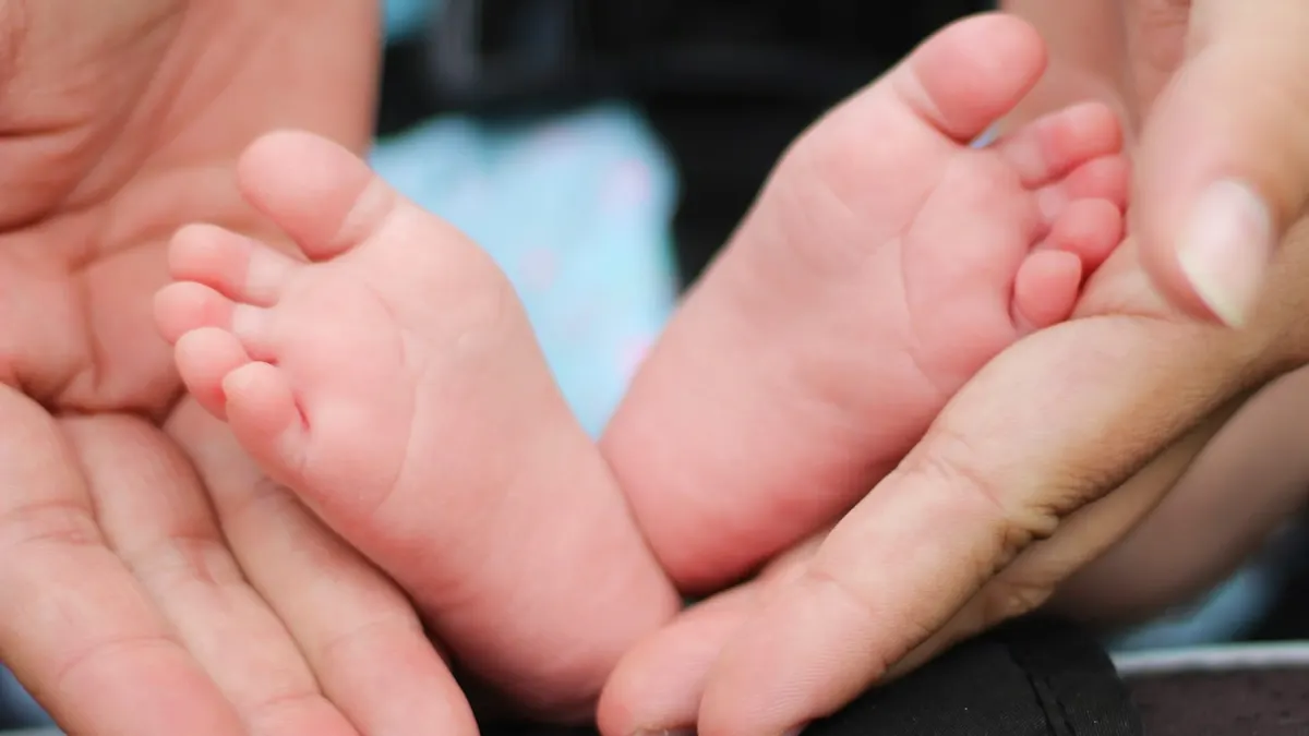 Piedini di un neonato tra le mani di un adulto