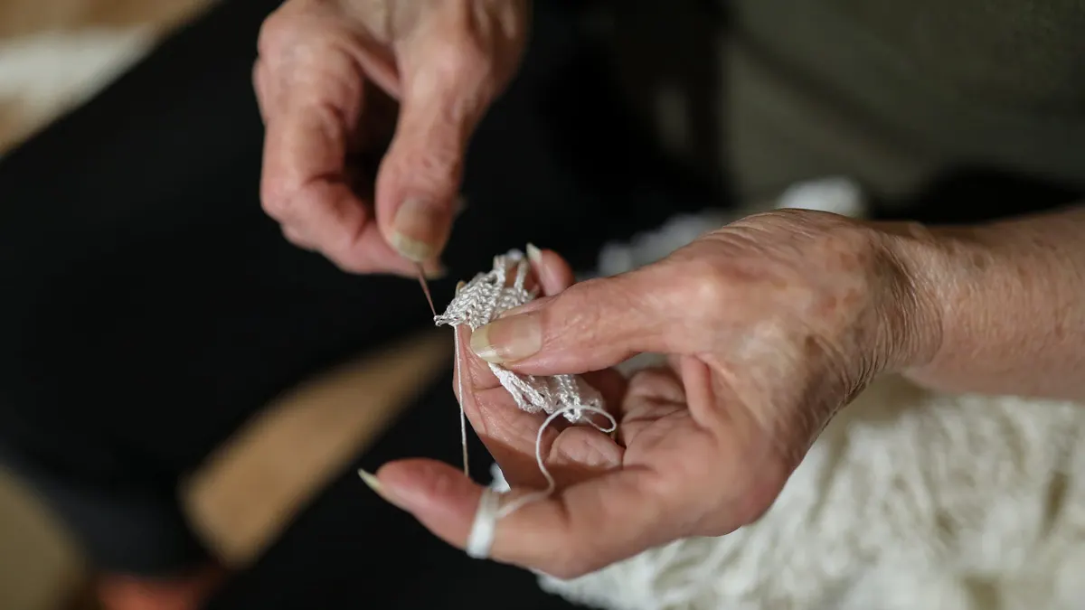 Mani di una donna anziana al lavoro a uncinetto