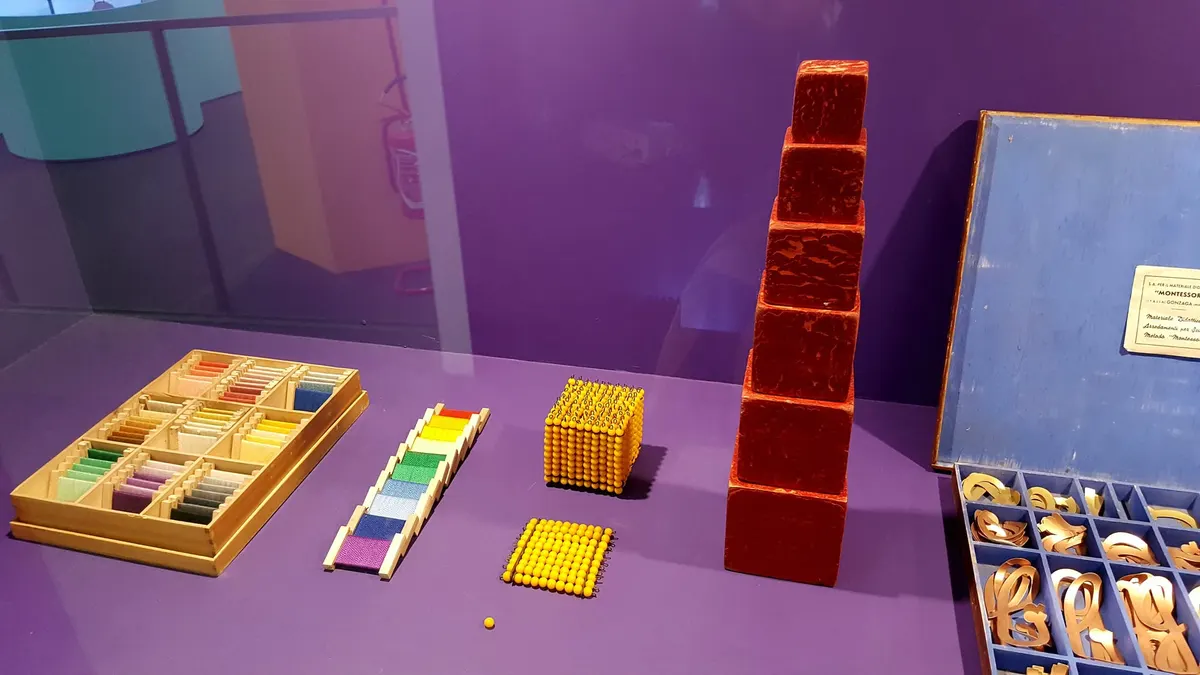 Materiali didattici del metodo Montessori esposti in una vetrina di museo