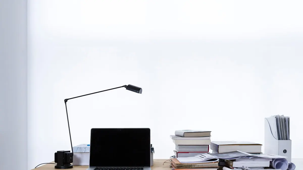 Un computer portatile su una scrivania con pile di libri