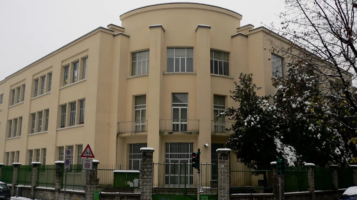 Edificio di una scuola italiana con la facciata color crema, ripreso in una giornata di neve