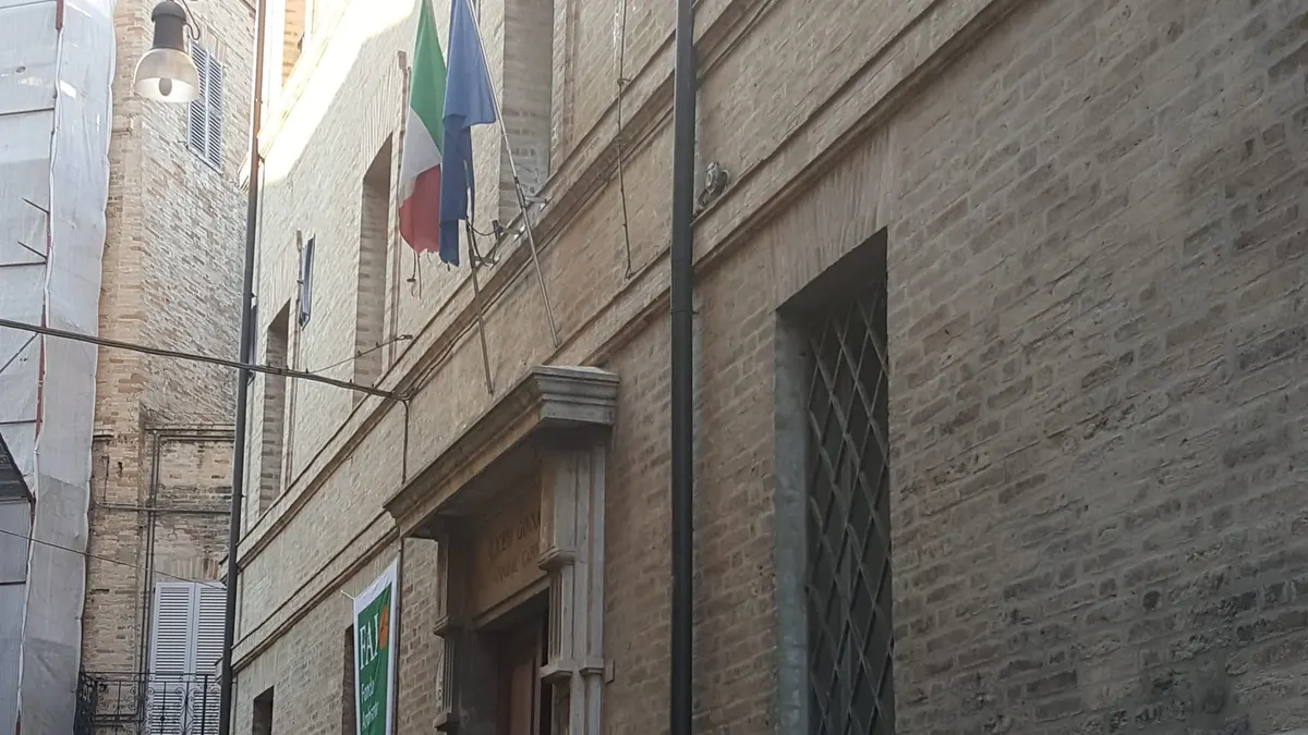 Ingresso di un liceo in una via del centro storico, con le bandiere italiana ed europea