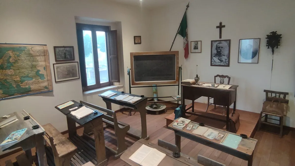 Aula scolastica d'epoca allestita in un museo, con banchi di legno e lavagna
